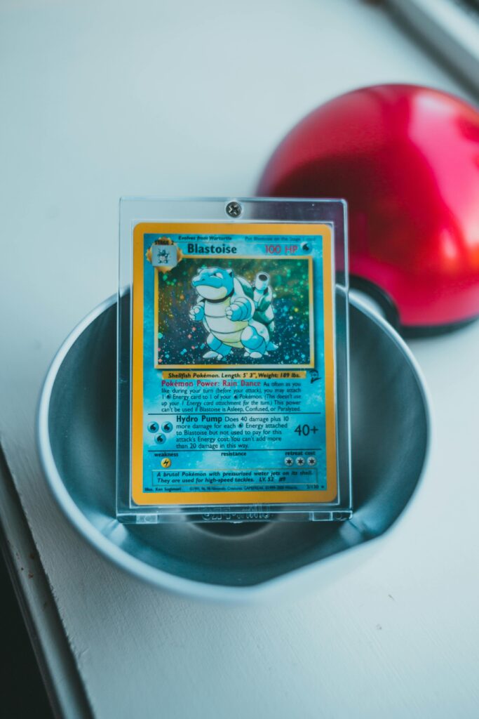 A holographic Blastoise Pokémon card displayed in protective casing with a Pokeball nearby.